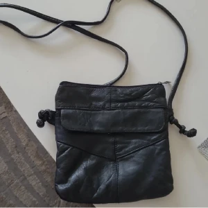 Väska - Vintage väska i skinnmaterial, vet ej märket på den. Enda "defekten" är att skinnet har lossnat lite från bandet, men inget som märks av vid anvädning. Kan fraktas med portokod för 18kr, men köparen står för frakten 💓