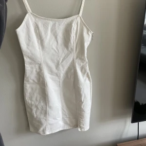 Jeansklänning  - Figursydd jeansklänning i vitt, aldrig använd 