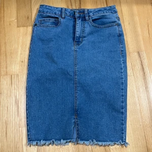 Jeanskjol  - Jeanskjol som går lite över knäna, med kort slits. 