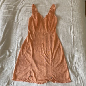 Laxrosa klänning  - Laxrosa / ljust orange klänning med söta volanger och blomdetaljer. Inköpt i vintagebutik och saknar märke. Aldrig använd av mig utan endast testad, i fint skick! 