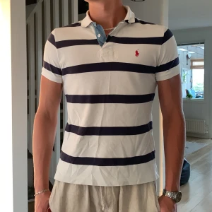 Polo Ralph Lauren pique - Riktigt snygg blåvit-randig Polo Ralph Lauren pique som jag köpte för 1255kr. Den är lite för liten för mig som är 187cm lång och använder den därför inte så ofta längre. Den är lite skrynklig på bilden men stryker den innan jag skickar. Först till kvarn!