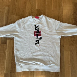 Hugo boss sweatshirt  - Fin Hugo boss tröja med asiatisk text och ett rött Hugo märke på bröstet storlek sx men den är stor i storleken så den passar s och även M möts bara upp i Malmö går att diskonteras