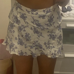 Kjol från Mango - Blå blommor på kjolen. Kjolen har en dragkedja i bak vid midjan. 