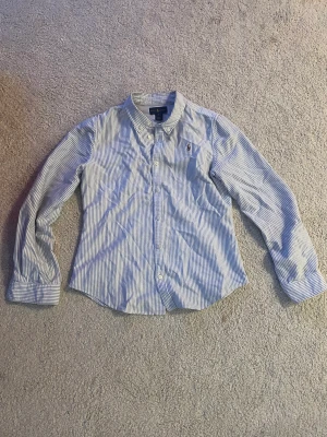 Ralph Lauren Skjorta - Randig Ralph lauren skjorta som är perfekt till sommaren.   Skjortan är i storlek 16 år som är motsvarar XS.