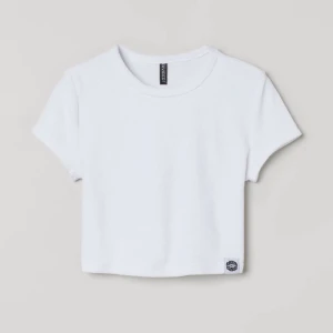 T shirt - Fin vit croppad t-shirt i coolt material från H&M. Inga fläckar och syns knappt att den är använd. Säljs för att den inte används längre. Köpt för 99kr och säljer för 25kr.