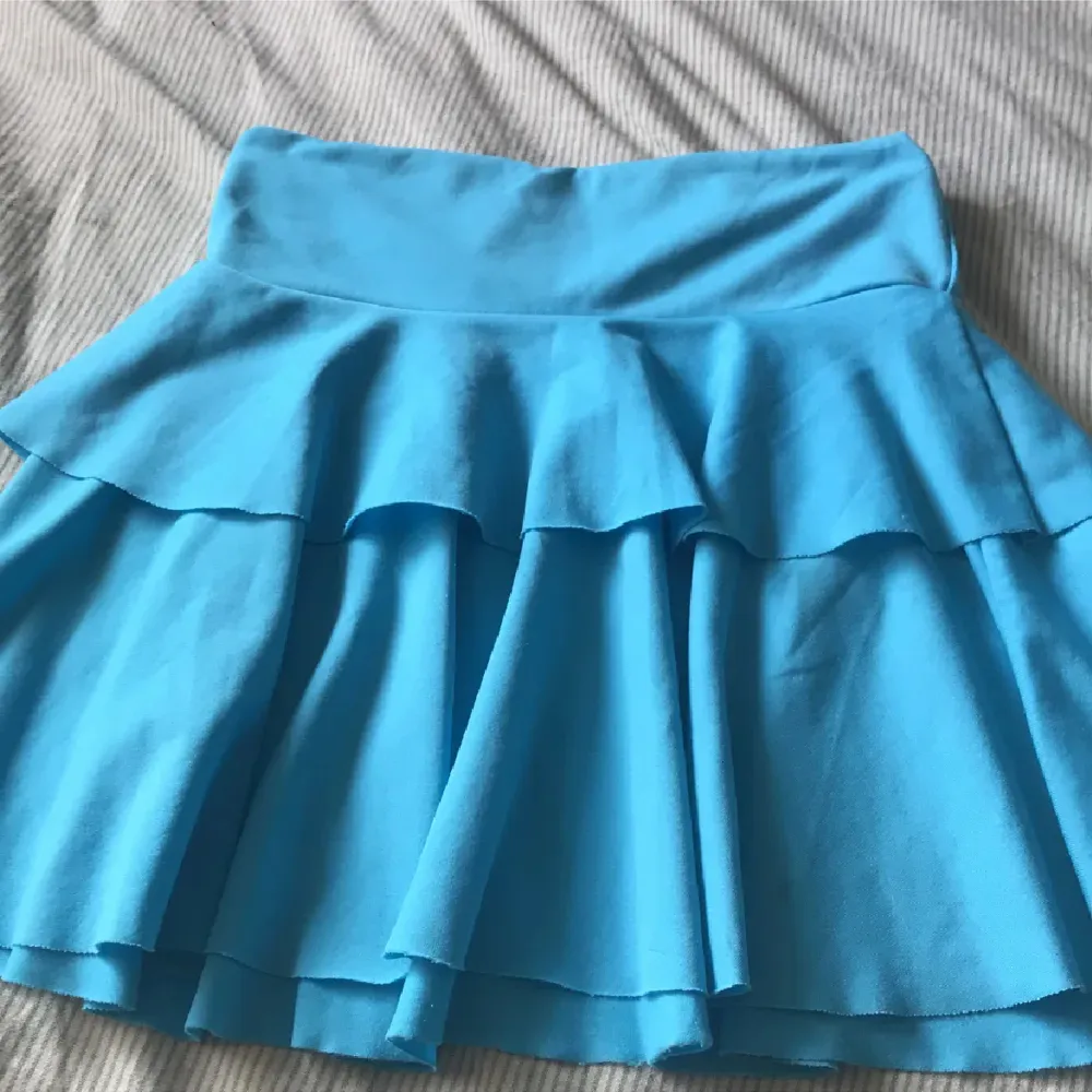 En blå vintage volangkjol. Har gått sönder längst ner vid kanten av kjolen (se bild 3). Kjolar.