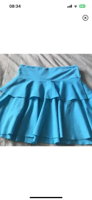 En blå vintage volangkjol. Har gått sönder längst ner vid kanten av kjolen (se bild 3)