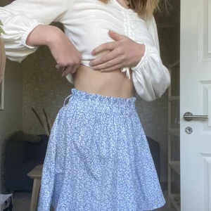 Blommig kort kjol - Blå blommig kjol! Typ aldrig använd Max 1 gång, alltså i nyskick. Medföljande band till den, se andra bilden. Som går att ta av, enligt mig behövs bandet inte. 🌸