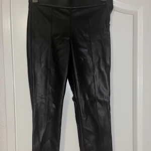 Skinnbyxor  - Svarta skinnbyxor med slits där nere och dragkedja åt sidan! Ingen stretch utan tajt material. 