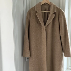 Kappa från & Other Stories - En otroligt fin höskappa i en camel / beige färg gjord av en ullblandning. Kappan är fint fodrad och är i nyskick! Kappan är i storlek 36 = S.
