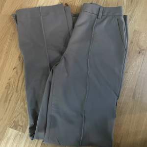 Säljer ett par gråa kostymbyxor från Nakd då de inte kommer till användning. Byxorna är midwaist och har slits på benen (se andra bilden). Fint skick då de knappt använts.