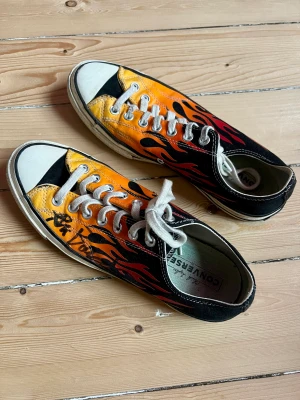 Converse ”All Star Flames” - Converse low ”All Star Flames” stl 42 i knappt använd schick. Säljs pg av att de inte passar längre. Den ena skorn är signerad av skateprofilen Ali Boulala under filmpremiären av hans dokumentärfilm.