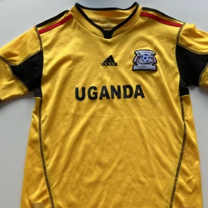 Uganda fotbolls kläder - Gult tränings sätt där det står Uganda på tröjan. Bra skick och billigt 