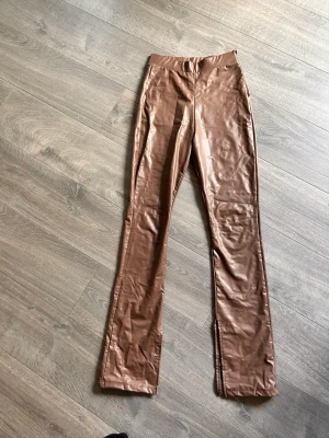 Brun skinnbyxa med slits - Brun skinnbyxa med sluta längst ner, från Nelly. Nyskick.
