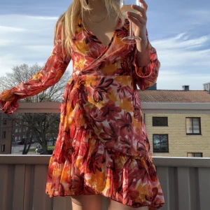 Sommarklänning  - Blommig långärmad sommarklänning från Gina Tricot!💛❤️🧡 Volanger nertill & på armarna, väldigt vacker & perfekt längd för mig som är 1,65m. Omlott, härligt material och passar till många tillfällen. Använd ett fåtal gånger och i mycket fint skick. Passar S.