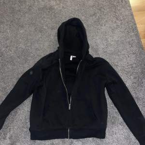 En svart zip hoodie från h&m. Lite kortare i längden. Köptes på h&m i Umeå.