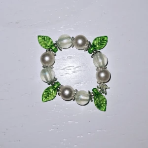 Ring med charm - Vita äkrylpärlor, blåa glitter pärlor, gröna blad och silverdetaljer. 