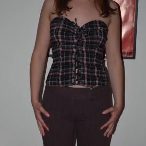 korsettliknande tube top  - Super söt svart- och rosa rutig korsettliknande tube top! I gott skick, använd 1-2 gånger. Säljer pga för liten för mig som är storlek M. Pruta funkar i majoriteten av fallen!