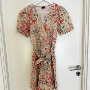 Blommig klänning - Superfin klänning från Gina Tricot. Knälång omlottklänning som knyts med ett skärp o midjan. I nyskick, endast använd en gång. Storlek 38.
