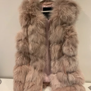 HOLLIES VÄST - Hollies - Äkta päls Använd fåtal gånger och väldigt fint skick! Jag är vanligtvis storlek 34/36 och denna sitter bra på mig trots storlek 40