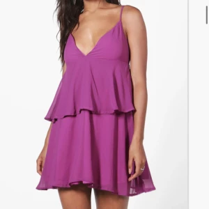 Lila klänning i strl 36 - Lila klänning i v-ringning och dragkedja baktill i strl. 36. Passar även strl 34. Oanvänd.