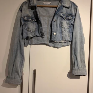 Jeansjacka - Avklippta jeansjacka. Jättefin till en vit klänning, jackan gör så att figuren i klänningen framhävs mer. Passar M/L