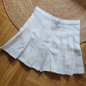 Vit kort kjol - Intressekoll på denna : Vit kort plisserad kjol med lagda veck. 66cm omkrets midjan. Längd ca 35cm. Stl S/XS. Ny! Aldrig använd. 
