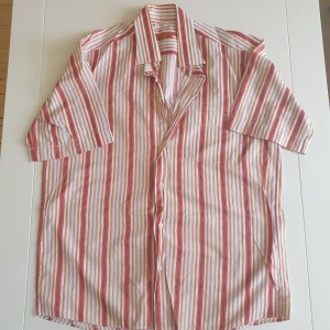 Skjorta - Röd-orangea-vit randig skjorta. Kan skicka fler bilder och tänka mig sänka priset. Hör av dig vid intresse!