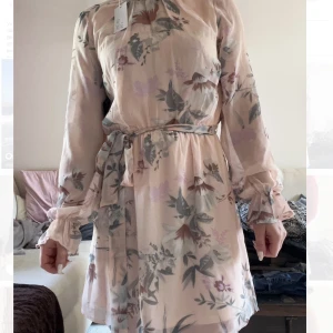 Klänning  - Klänning från Nelly i storlek 34. Oanvänd med prislappen kvar. Perfekt för bröllop eller dop. Väldigt fin färg oxh härligt tyg. Den har tyvärr aldrig kommit till användning för mig 