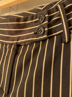 Randiga kostymbyxor  - Superfina randiga kostymbyxor som är flared och lowrise. Älskar knäppningen och känns business casual! Säljer för att de inte passar!