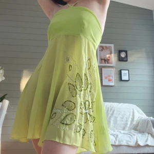 Klänning - Drömmig kort grön meshklänning med knytband i nacken och superfina paljettdetaljer💚Nedre kjoldelen av klänningen är i mesh-halvgenomskinligt tyg så passar utmärkt att bära tex en underkjol under om man vill💚Fint begagnat skick✨️2000tals vibes! Jag är 160cm