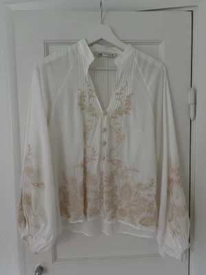 Blus med broderi  - Superfin vit blus med beige broderi från Zara. Köpt i våras, använd en gång så är i fint skick!