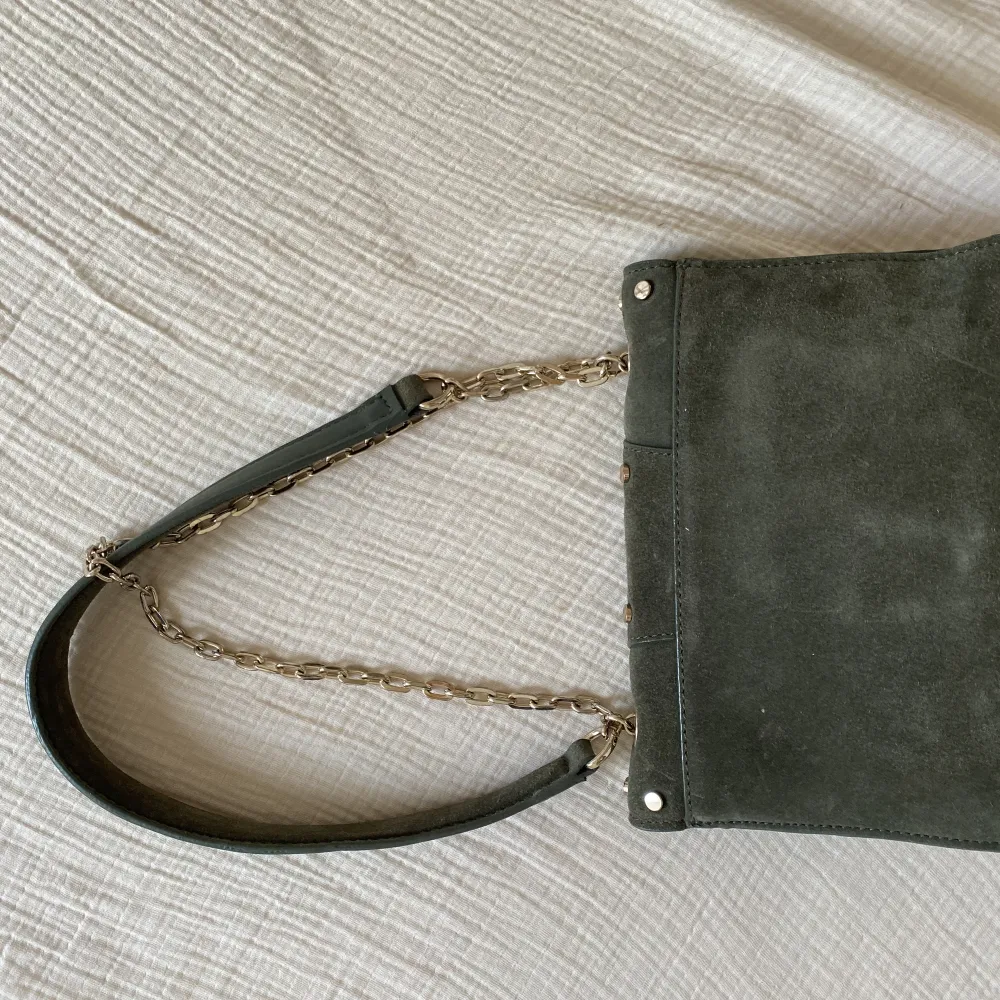 Väska i grön trendig mocca med axelband som går att bära långt eller kort. Praktiska fickor på insidan. Ca 20x15cm. Väskor.