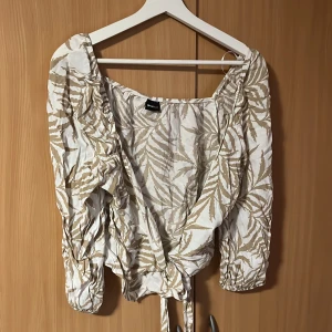 Tie Front Blouse - Vit & Beige tie front blus från Gina Tricot  Storlek 40.  Helt oanvänd. 2:à bilden är med blixten på. Vid övriga frågor eller fler bilder få ni gärna skriva🤍🤎