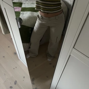 Beiga cargobyxor - Low-waisted cargobyxor med många detaljer såsom fickor och dragsko längst ner. Köpta second hand och är i väldigt fint skick!🤎