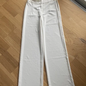 Vita kostymbyxor  - Oanvända vita kostymbyxor från Bikbok. Ena lappen sitter fortfarande kvar. Säljer pga att de aldrig kommer till användning. Nypris 300kr.
