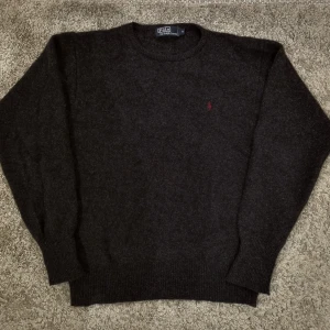 Ralph Lauren Ulltröja - Säljer nu min lite äldre Polo Ralph Lauren ylletröja. Den är i 100% lammull. Trots att den är äldre så är den i bra skick och det är inga defekter. Färgen är väldigt mörkgrå och märket är vinrött.