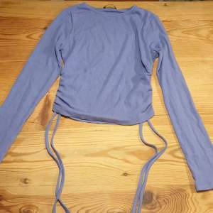 En blå långärmad tröja med snören och räfflat på sidan.