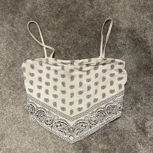 Topp med knytning bak - Vit top med sött mönster. Knyter och justerar hur tajt man vill ha den där bak. Skönt material och passar bra när man ska utomlands eller resa. Köpt från New yorker och är i storlek S men funkar nog för XS och M också.