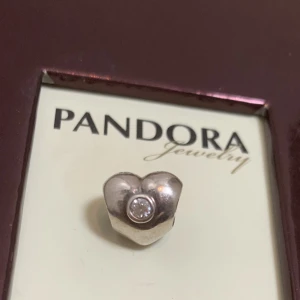 Pandora berlock nyskick retired  - Berlock i sterling silver,aldrig använt. Legat i original förpackning tillsammans med andra berlocker sen 2005/06. Ingen egen ask. Tillverkas ej mer. Märkt 925/ALE (pandoras stämpel) Heter: Retired Sterling Silver Heart Charm with Clear Zirconia - 790134C