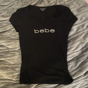 Bebe tröja - Jättefin top från Bebe! Storlek XS men den är Stretchig, kan passa XS-S eventuellt M. Den är klippt så att den är v-neck! 