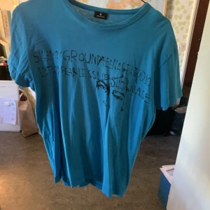 Blå T-Shirt med tryck - Häftig blå t-shirt från Selected. Unikt tryck och i väldigt bra skick. Storlek S.