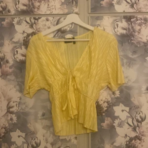 Kortärmad topp - En kortärmad tröja med två knytningar framtill och den är ribbad,  i storlek 36. Aldrig använd så i fint skick! 