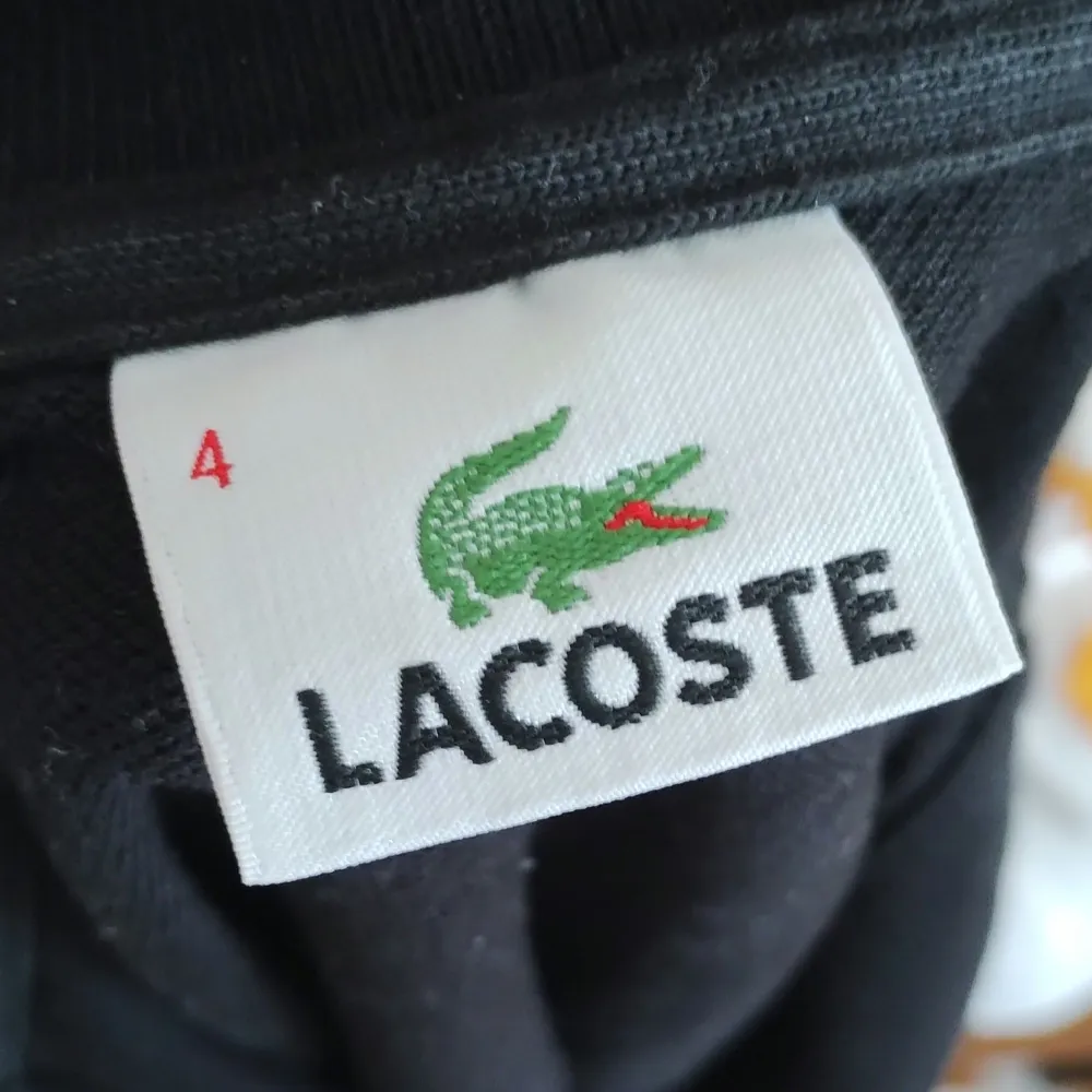 Svart långärmad Lacoste piké. Sparsamt använd. Storlek: 4.. T-shirts.