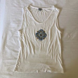 Vitt linne med pärlbroderi strl S  - Somrigt linne med blå pärlbroderier på framsidan. I gott skick, från märket henry lord, strl S. Köparen står för frakt. Dma gärna vid frågor eller funderingar! 