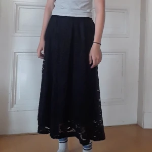 Maxikjol med spets - Svart maxikjol med blommigt spetsmönster. Har resår runt midjan så kan vara både high och lowrise. Tyvärr är spetsmönstret lite knopprigt och sönder på vissa ställen, kontakta för bilder. (Har också fickor som inte syns)