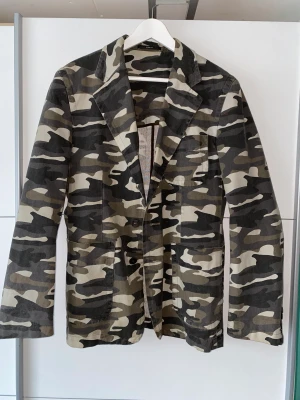 EMILIO X CAMOUFLAGE KAVAJ - 00-talets Emilio camouflage mönstrad kavaj/jacka från MQ. Perfekt för våren och hösten. Material: 100% Bommul. Fordring 100% Polyester. Storlek: 48/EU M. Skick: 8/10. 
