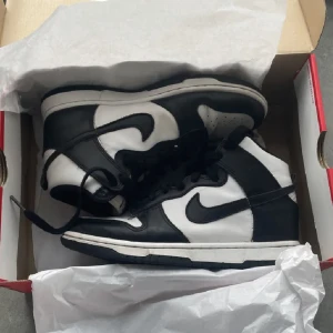 Nike dunks high panda sneakers i storlek 38 W size  - Nike dunks high panda i storlek 38 W size  Använt ett par gånger. Skorna är äkta och i bra skick bedöm från bilderna.  Orginalkartong medföljer.