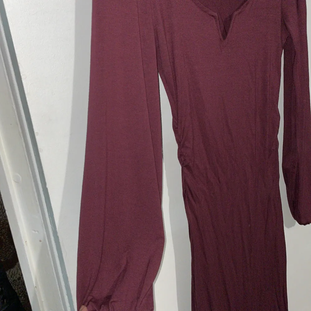 Detta är en relativt lång klänning (som kommer mig som är 173cm lång precis över knäna), i en fin vinröd färg, som sitter tajt på kroppen. . Klänningar.