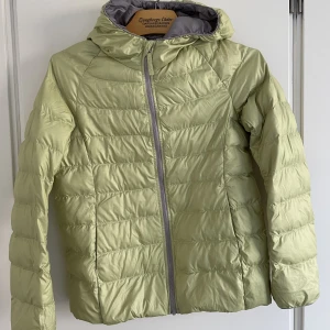 Uniqlo lättviktsjacka 146 - Otroligt lätt jacka från Uniqlo. Lime gröngul med grått foder. Fast luva och två fickor.   Perfekt höst/vår jacka eller som extra jacka att ha i ryggan på utflykten.   Väldigt bra skick, Inga fläckar el slitningar. 